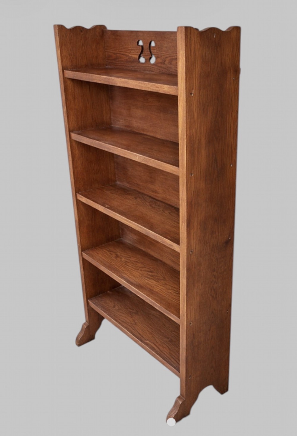 An early twentieth-century Arts and Crafts solid oak open bookcase featuring five shelves and a carved cut-out motif at the top. View II