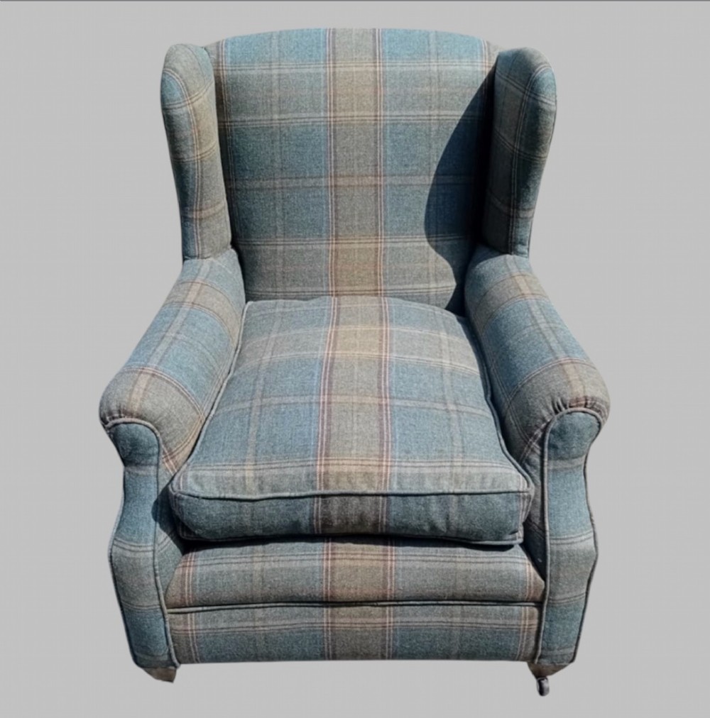 A traditional English wingback armchair upholstered in a teal and tan plaid Shetland wool pattern with turned front legs on brass castors. View II