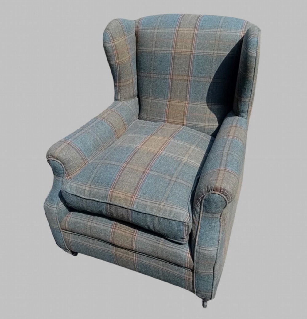 A traditional English wingback armchair upholstered in a teal and tan plaid Shetland wool pattern with turned front legs on brass castors. View III
