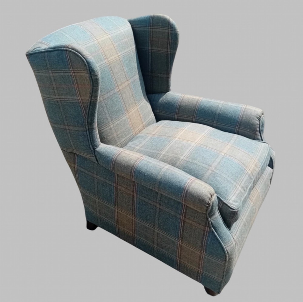 A traditional English wingback armchair upholstered in a teal and tan plaid Shetland wool pattern with turned front legs on brass castors. View IV