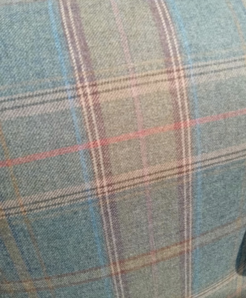 A traditional English wingback armchair upholstered in a teal and tan plaid Shetland wool pattern with turned front legs on brass castors. View VII