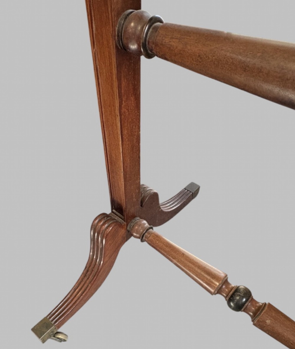A nineteenth-century flame mahogany cheval mirror featuring turned side uprights, top finials, reeded splayed legs, and brass castors. View III