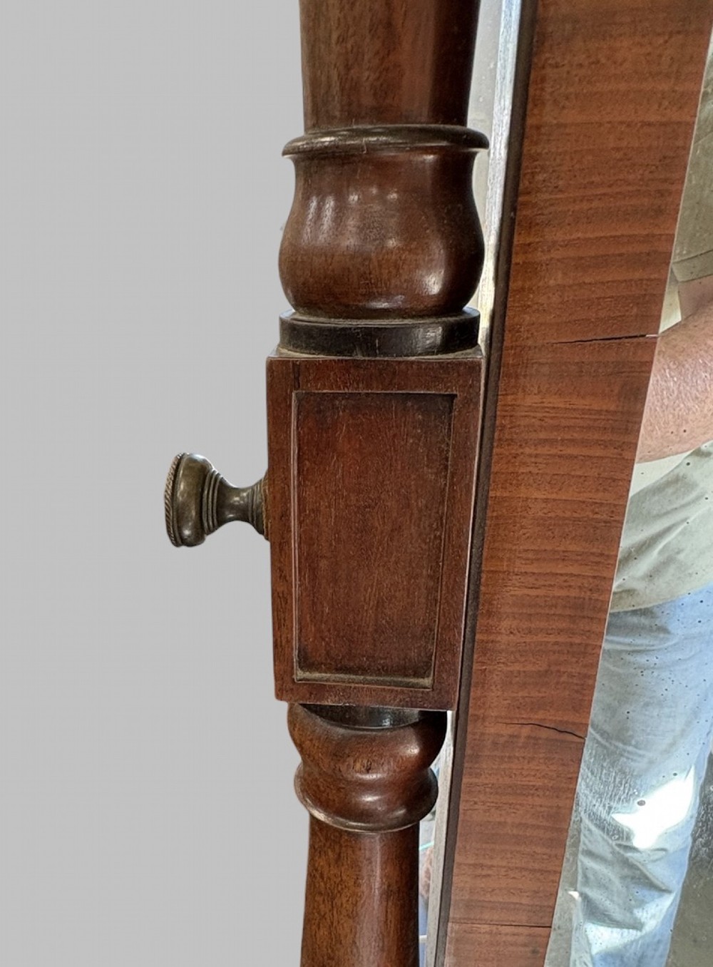 A nineteenth-century flame mahogany cheval mirror featuring turned side uprights, top finials, reeded splayed legs, and brass castors. View V