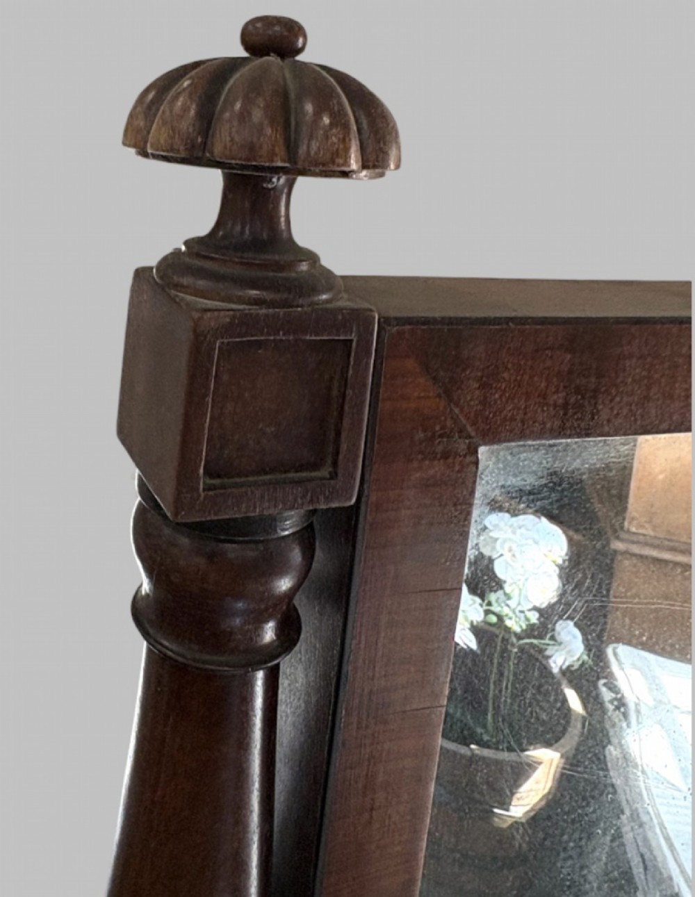 A nineteenth-century flame mahogany cheval mirror featuring turned side uprights, top finials, reeded splayed legs, and brass castors. View VI