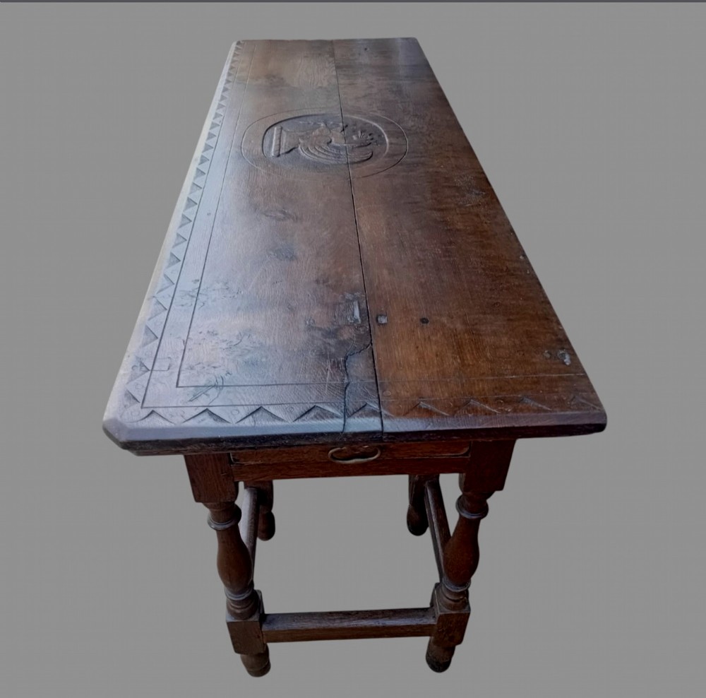 A dark oak hall table featuring turned legs, lower perimeter stretchers, a carved scrollwork frieze, and a carved central medallion on the top surface. View II