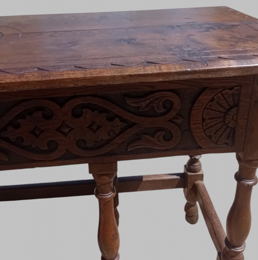 A dark oak hall table featuring turned legs, lower perimeter stretchers, a carved scrollwork frieze, and a carved central medallion on the top surface. View VI