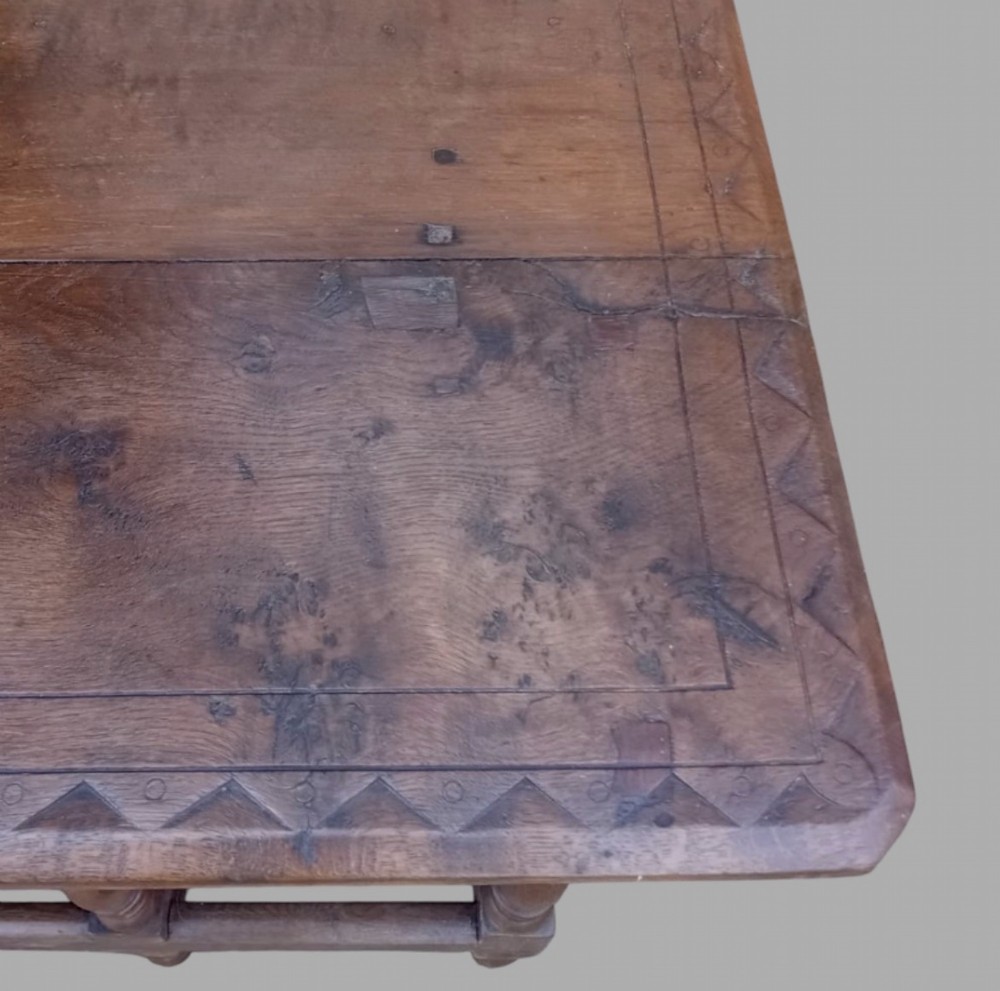 A dark oak hall table featuring turned legs, lower perimeter stretchers, a carved scrollwork frieze, and a carved central medallion on the top surface. View VIII