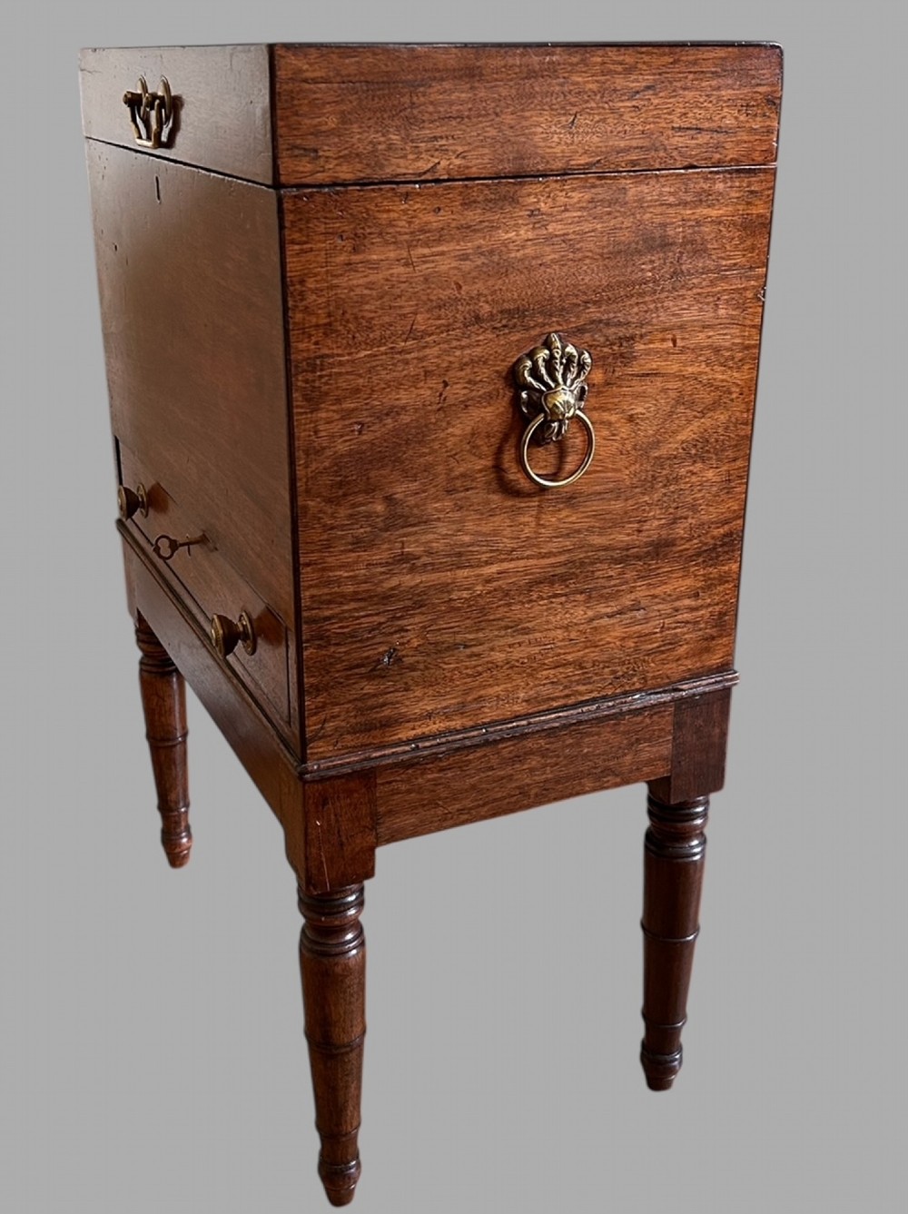 A Georgian mahogany wine cellarette featuring a hinged lid with a top brass handle, keyhole, lower drawer, and four turned legs. View IV