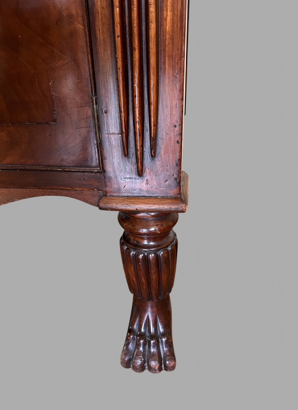 A 19th-century flame mahogany sideboard featuring two upper drawers, two cabinet doors, reeded pilasters, oval brass handles, a low gallery back, and carved paw feet. View VI