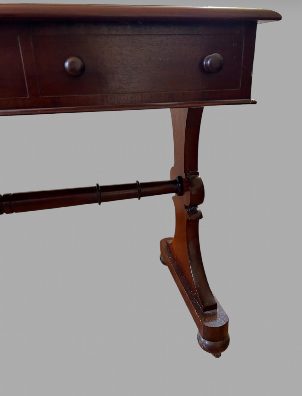 A rectangular mahogany library table featuring three frieze drawers with round timber handles and a lower turned stretcher resting on shaped trestle feet. View V