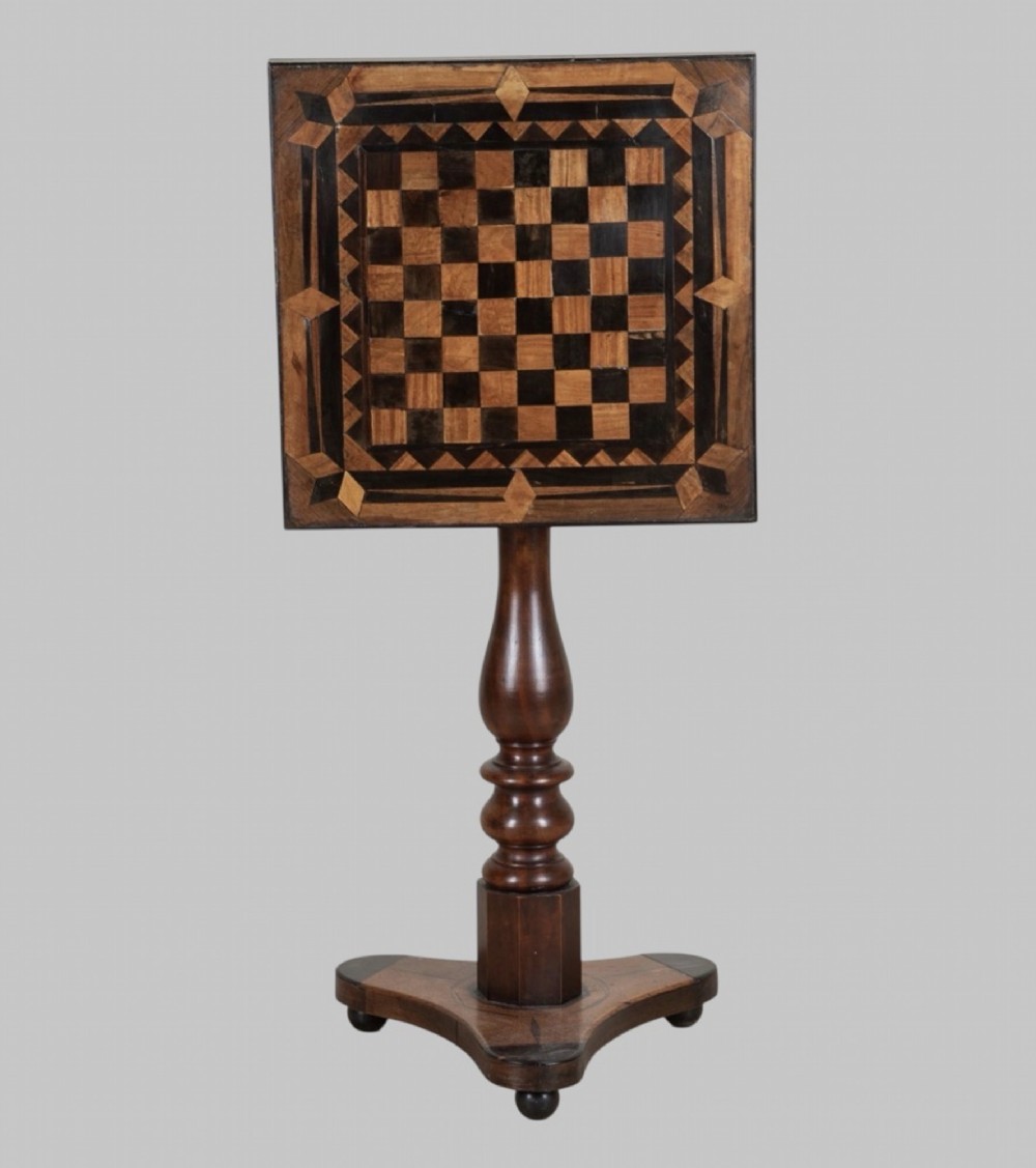 A Georgian tilt-top games table with a square geometric inlaid chessboard top mounted on a turned pedestal column and triform base with ball feet.