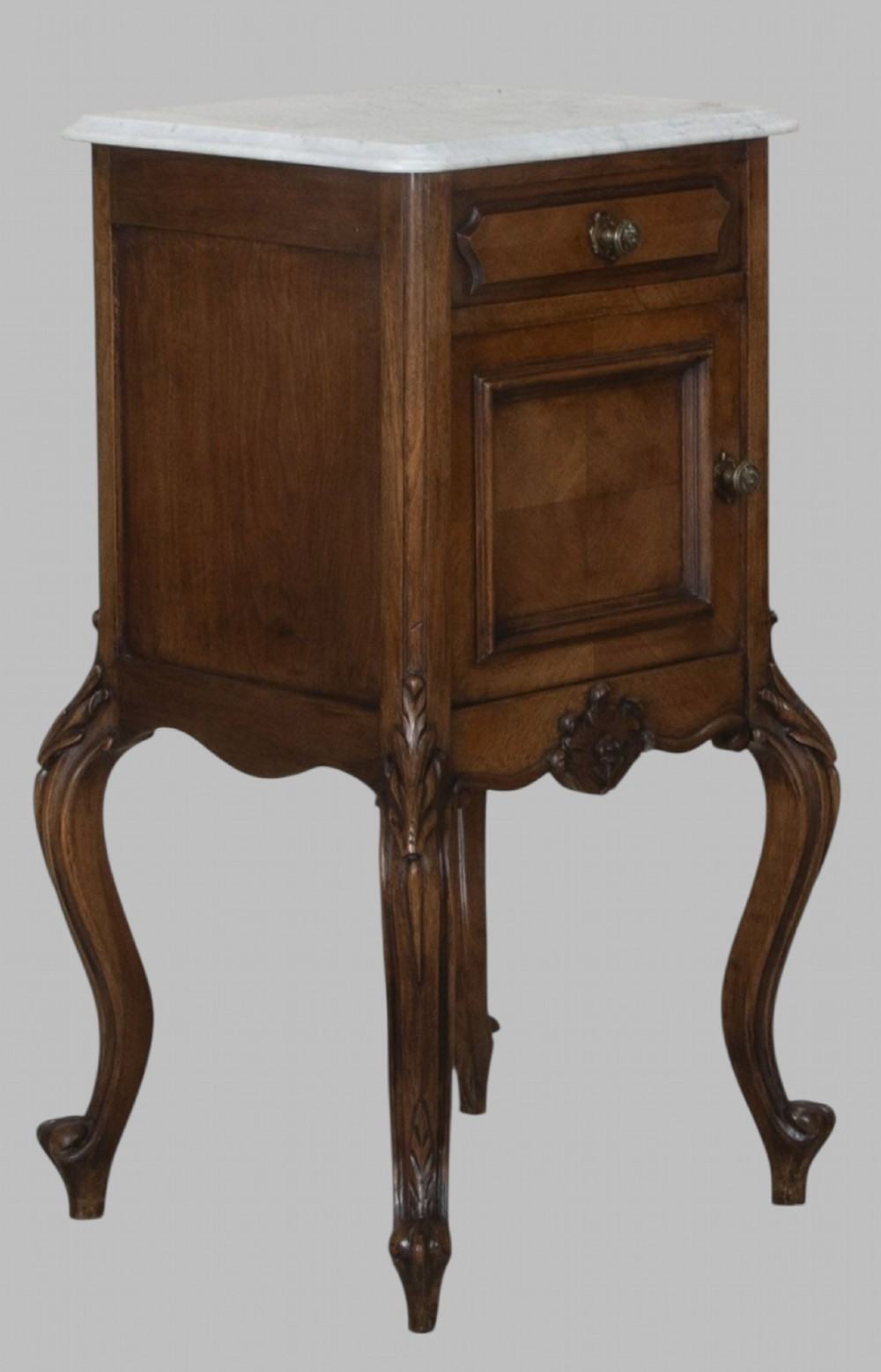 A pair of French walnut bedside cabinets featuring white marble tops, single drawers over cupboard doors, carved aprons, and slender cabriole legs. View IV