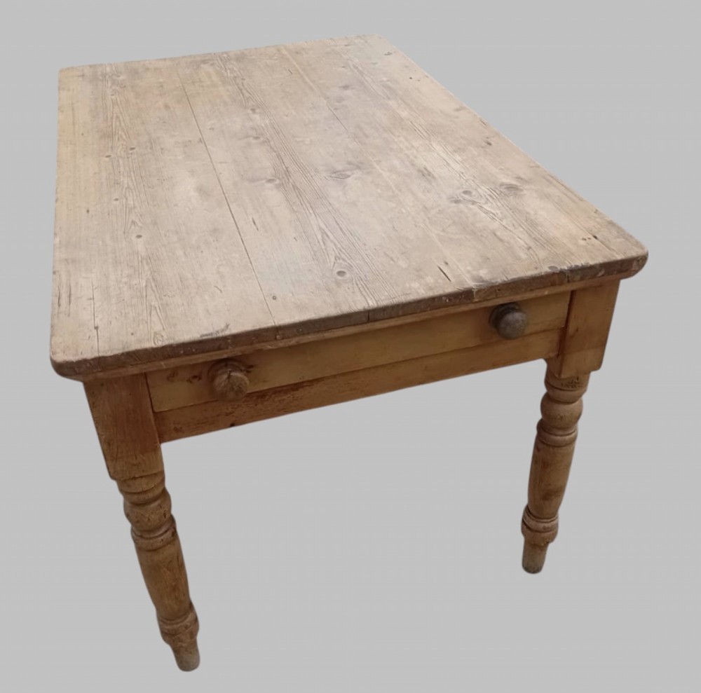 A late 19th-century rectangular pine farmhouse table featuring a scrubbed wood plank top, a frieze drawer with turned wooden knobs, and turned legs.