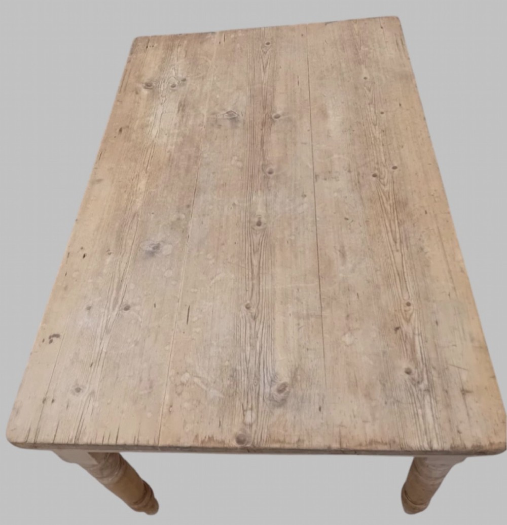 A late 19th-century rectangular pine farmhouse table featuring a scrubbed wood plank top, a frieze drawer with turned wooden knobs, and turned legs. View IV