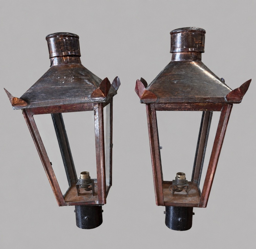 A pair of tapered copper post lanterns featuring clear glass side panels, cylindrical top chimneys, corner fins, and black collar mounts. View II
