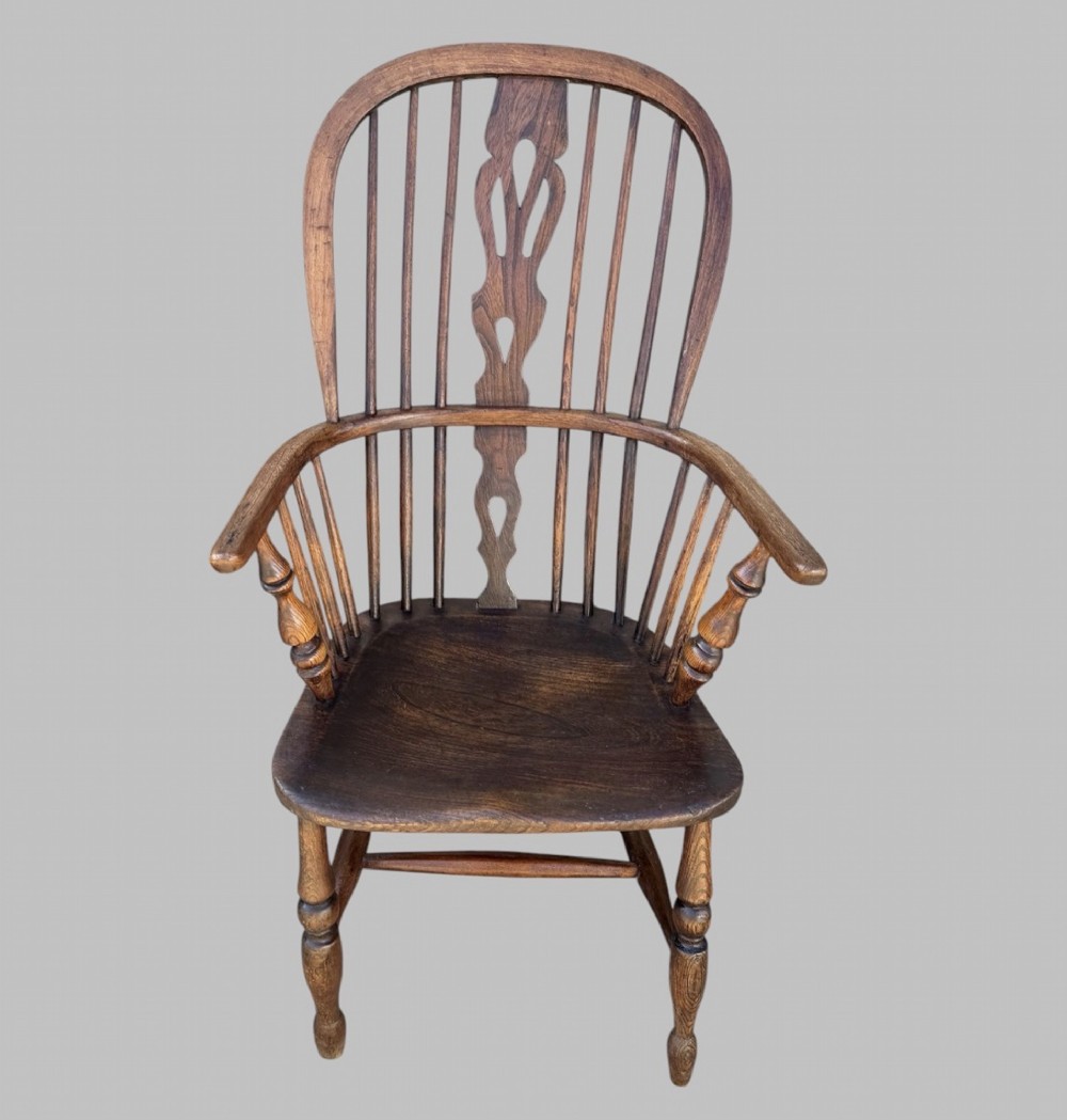 A nineteenth-century hoop-back Windsor armchair crafted from ash and elm wood, featuring a shaped saddle seat, pierced splat, slender back spindles, turned front legs, and an H-stretcher.