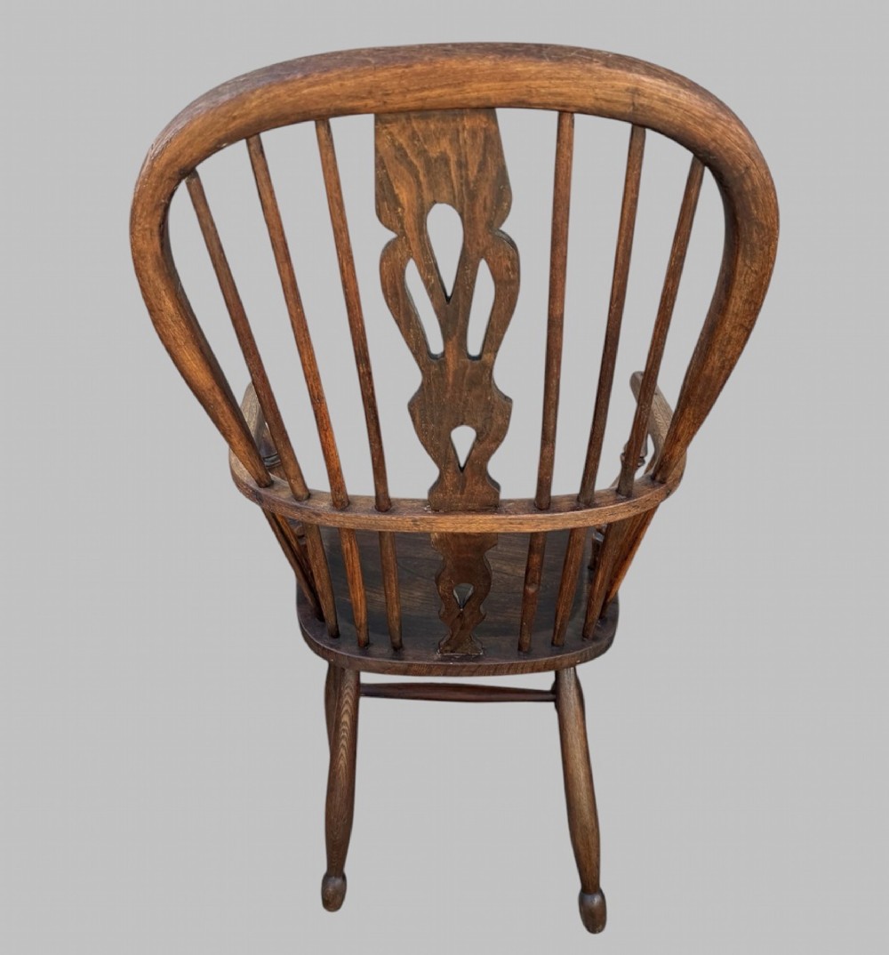 A nineteenth-century hoop-back Windsor armchair crafted from ash and elm wood, featuring a shaped saddle seat, pierced splat, slender back spindles, turned front legs, and an H-stretcher. View IV