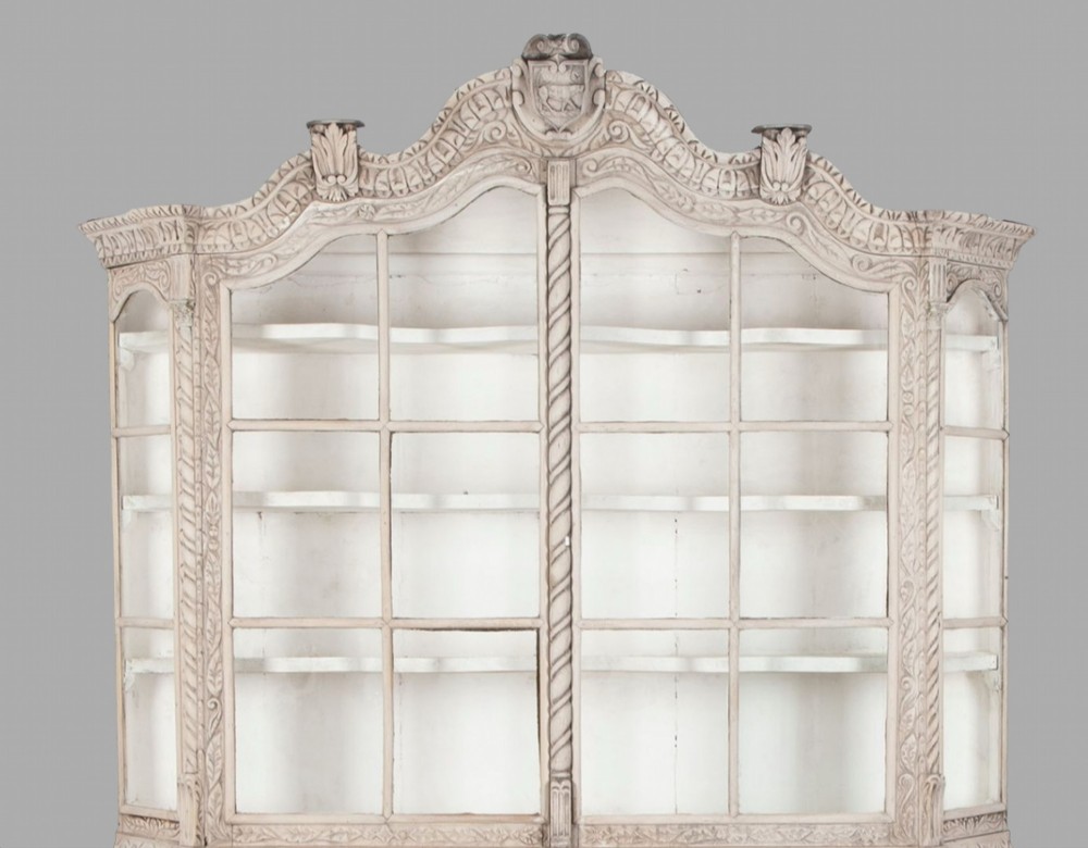A tall nineteenth-century Dutch carved pale oak display cabinet featuring a shaped crest, multi-pane glazed upper doors, and a bombe chest base with three relief-carved drawers on paw feet. View V