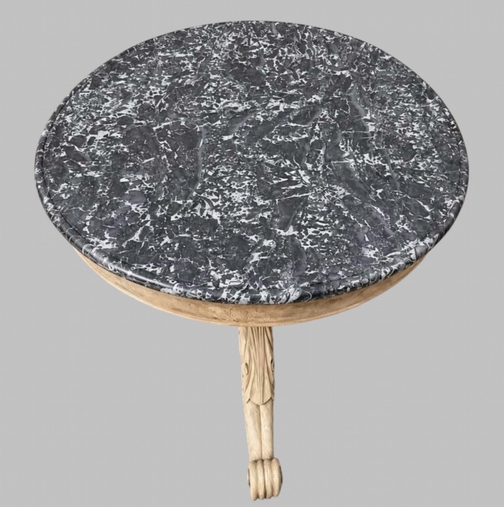 A circular antique French gueridon table featuring a dark grey mottled marble top supported by a carved bleached walnut pedestal and tripod scrolled legs. View II
