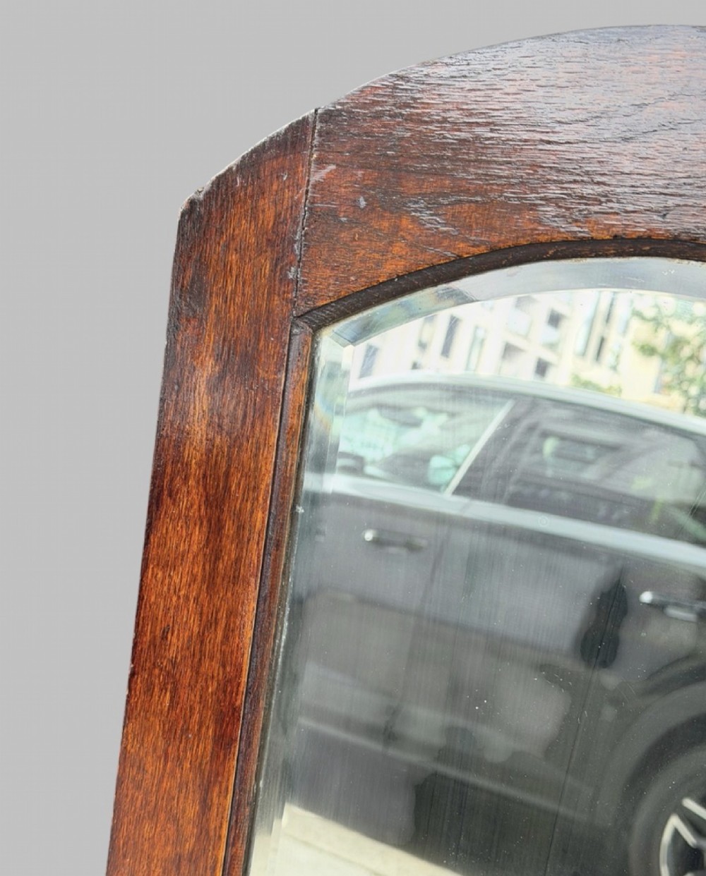 An early twentieth-century arched wall mirror set within a dark oak frame with a bevelled glass plate. View II
