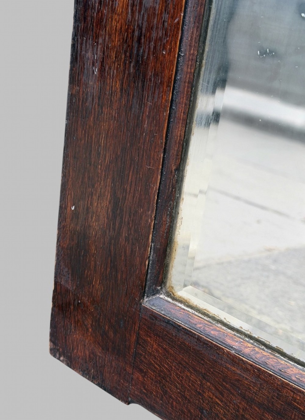 An early twentieth-century arched wall mirror set within a dark oak frame with a bevelled glass plate. View III