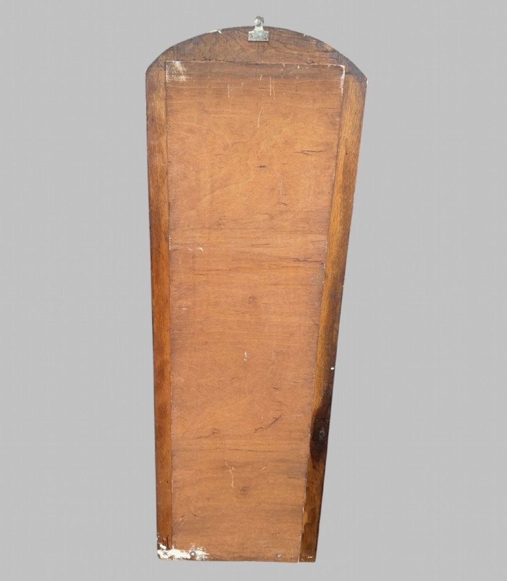 An early twentieth-century arched wall mirror set within a dark oak frame with a bevelled glass plate. View V