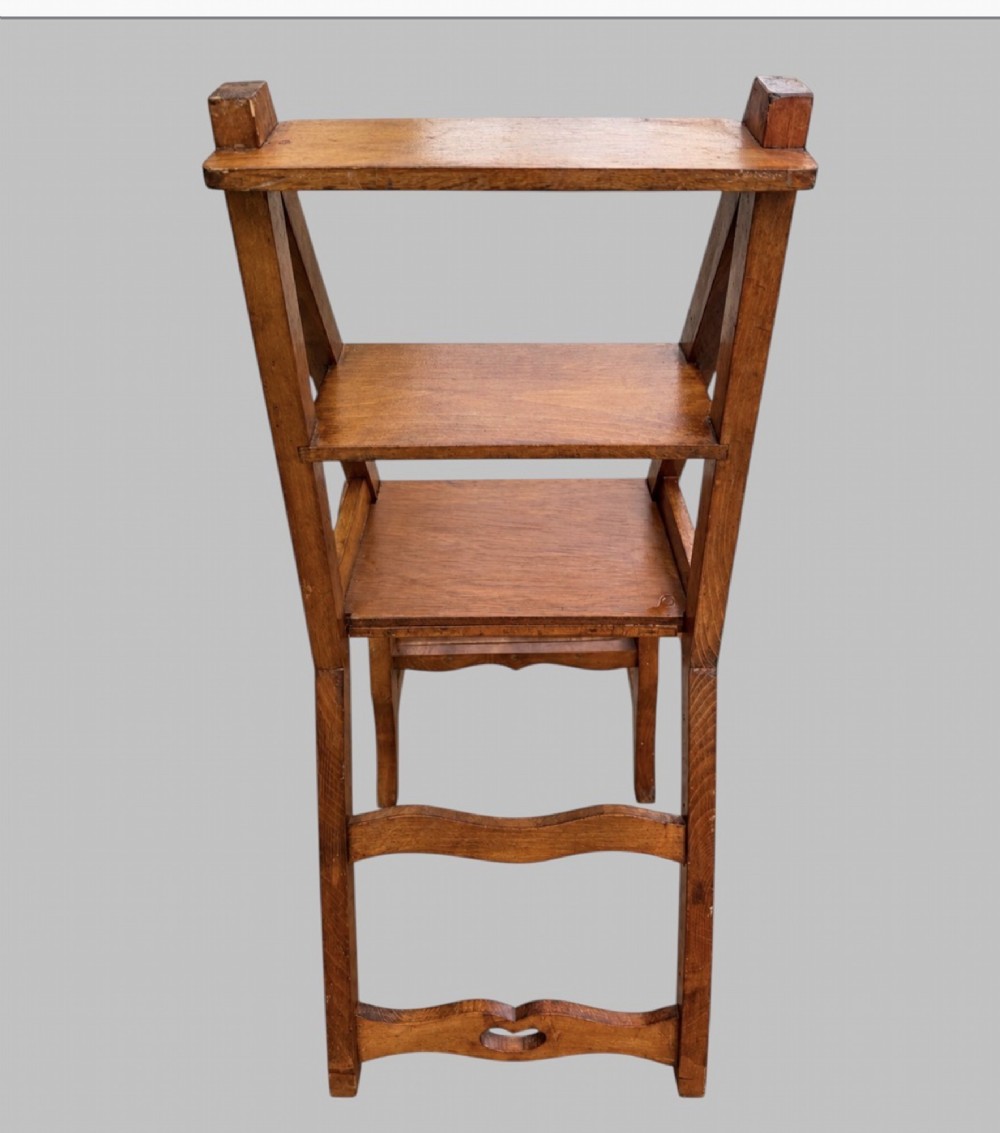 An Arts and Crafts style warm brown oak metamorphic library chair featuring a pierced heart-shaped cutout on the top rail and a hinged seat mechanism. View III