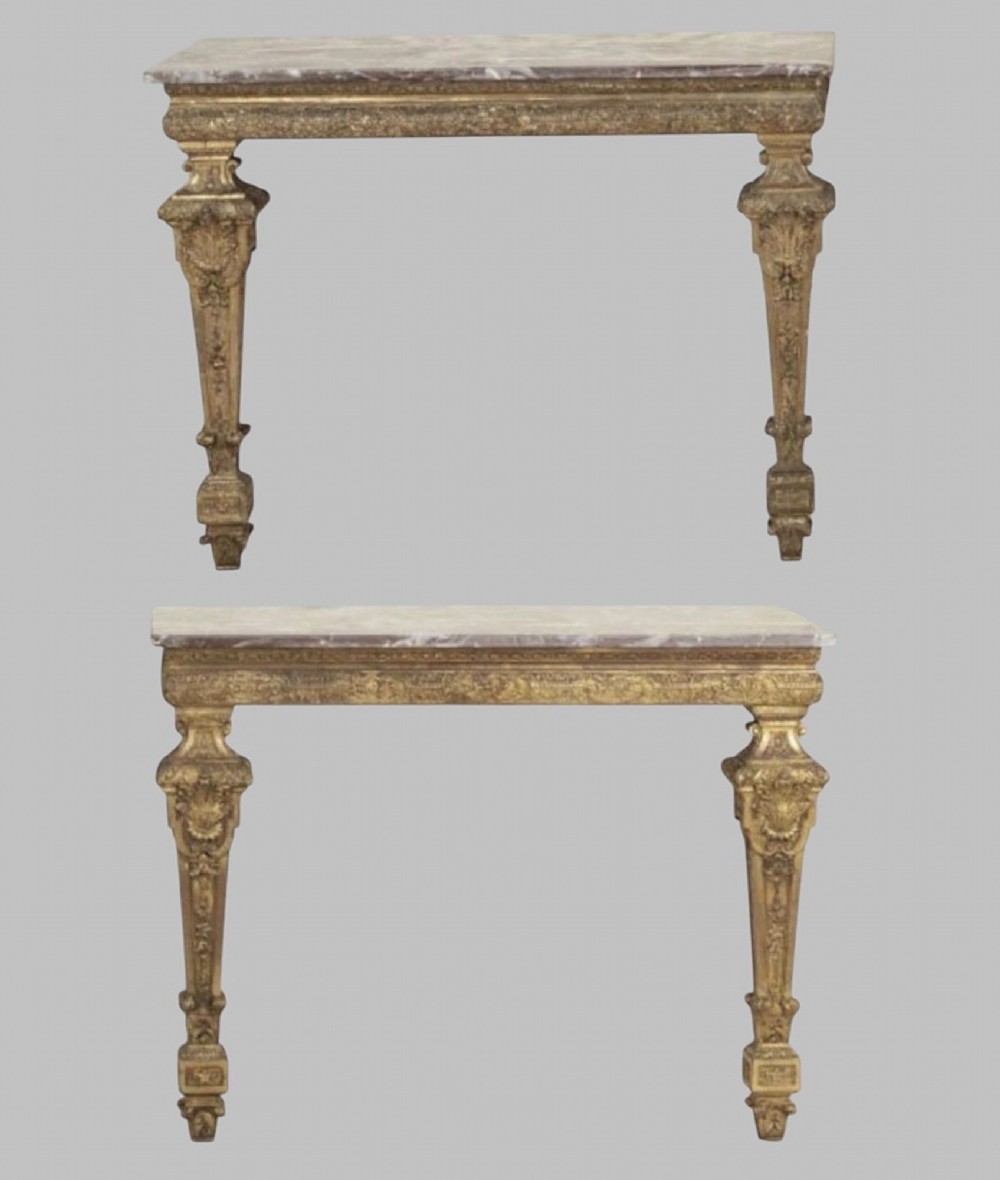A pair of 19th-century Italian giltwood console tables featuring carved tapered legs and fitted marble tops.