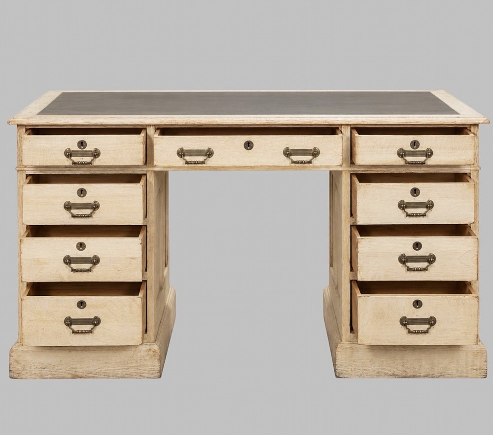 A circa 1900 bleached oak pedestal desk featuring nine drawers with brass swing handles and a dark inset leather writing surface. View II
