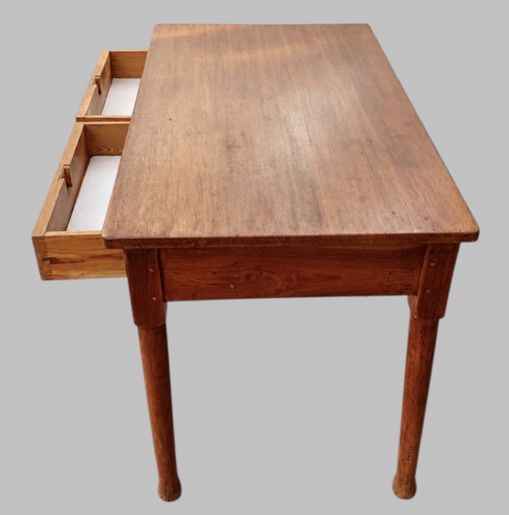 An early 20th-century light oak work table featuring a rectangular top, two frieze drawers with brass cup handles, and turned legs. View II