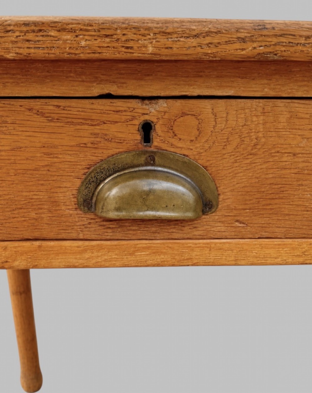 An early 20th-century light oak work table featuring a rectangular top, two frieze drawers with brass cup handles, and turned legs. View IV