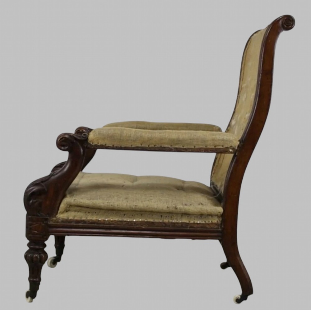 Side profile of a William IV carved oak armchair with upholstered seat, scrolled arms, turned front legs, and castors.
