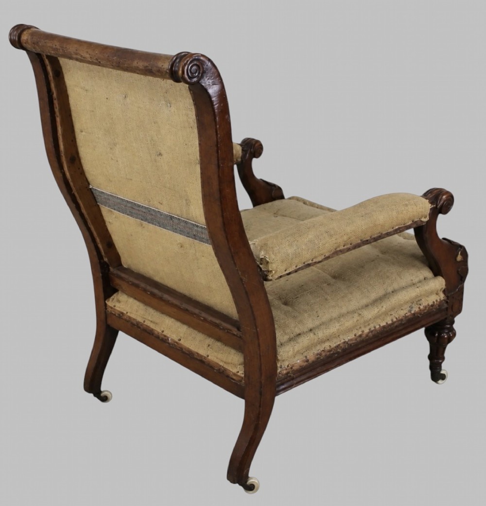 Side profile of a William IV carved oak armchair with upholstered seat, scrolled arms, turned front legs, and castors. View III