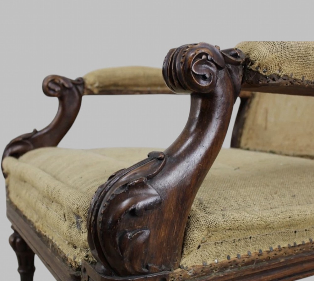 Side profile of a William IV carved oak armchair with upholstered seat, scrolled arms, turned front legs, and castors. View IV