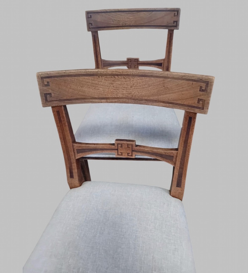 A set of six late 19th-century mahogany dining chairs with geometric marquetry inlay and light grey upholstered seats. View V