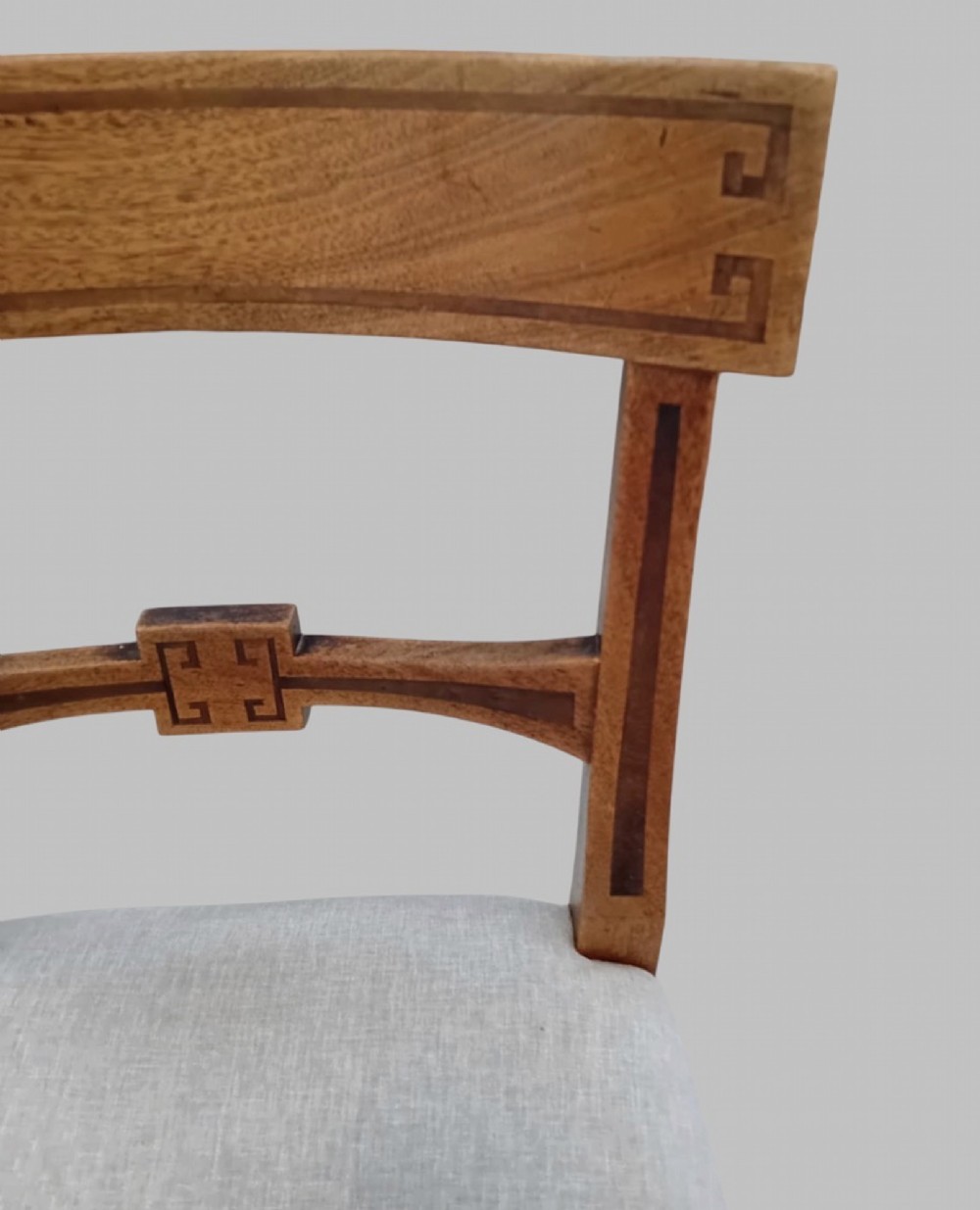 A set of six late 19th-century mahogany dining chairs with geometric marquetry inlay and light grey upholstered seats. View VI