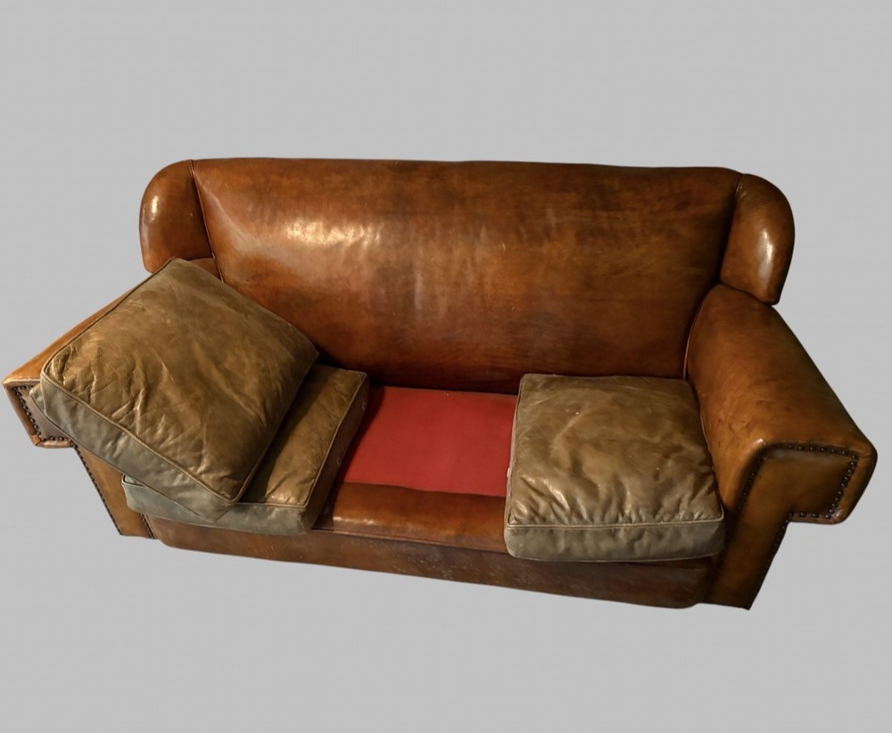 A three-seater Art Deco sofa upholstered in warm brown patinated leather with metal studding along the armrests. View VIII