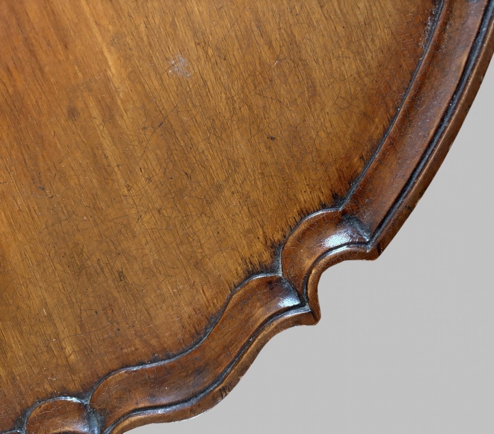 A dark mahogany tripod table featuring a circular pie-crust scalloped top, a turned central column with a birdcage block, and three cabriole legs ending in pad feet. View IV