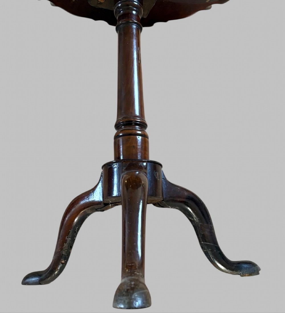 A dark mahogany tripod table featuring a circular pie-crust scalloped top, a turned central column with a birdcage block, and three cabriole legs ending in pad feet. View V