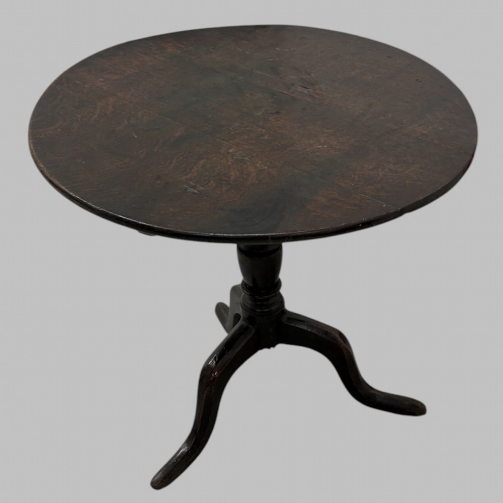 A 19th-century dark mahogany tilt-top table featuring a circular top, turned central column, and three splayed legs.