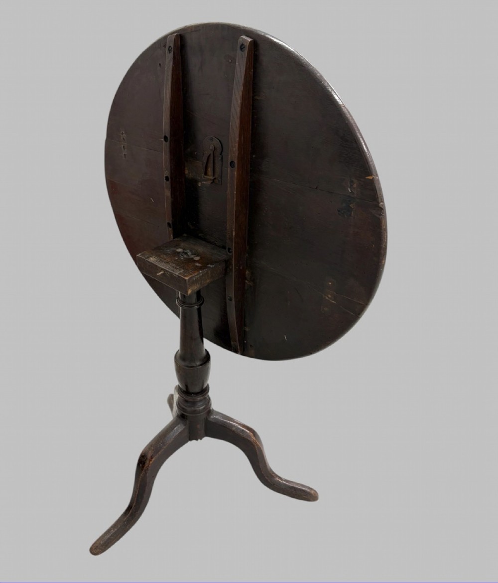 A 19th-century dark mahogany tilt-top table featuring a circular top, turned central column, and three splayed legs. View V