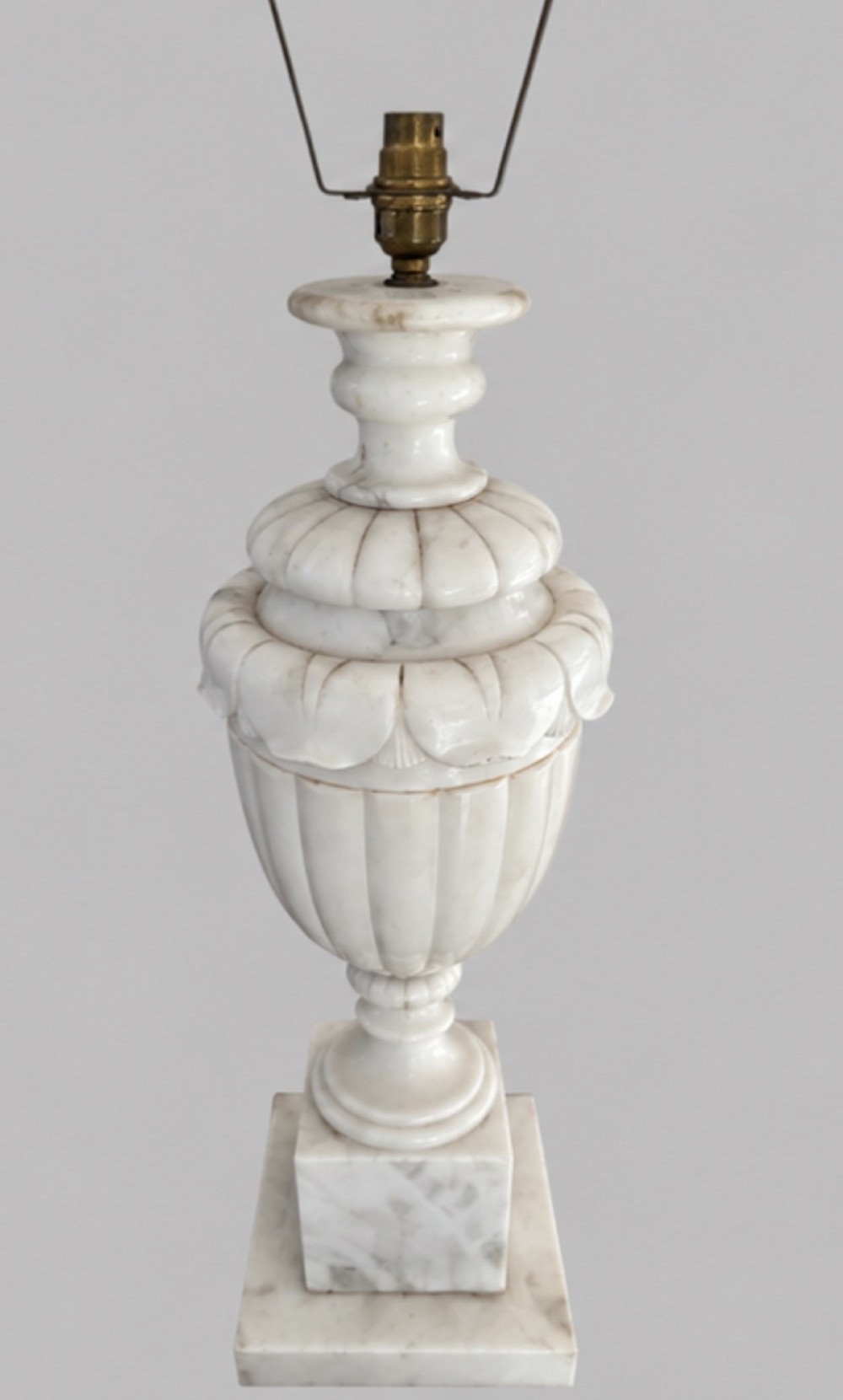 A carved off-white alabaster table lamp base shaped like a classical urn with leaf motifs, resting on a stepped square plinth with a brass harp socket. View II