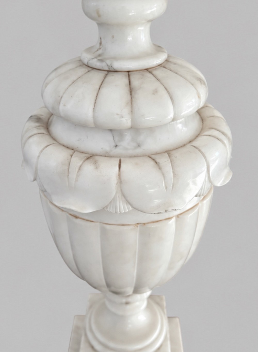 A carved off-white alabaster table lamp base shaped like a classical urn with leaf motifs, resting on a stepped square plinth with a brass harp socket. View IV