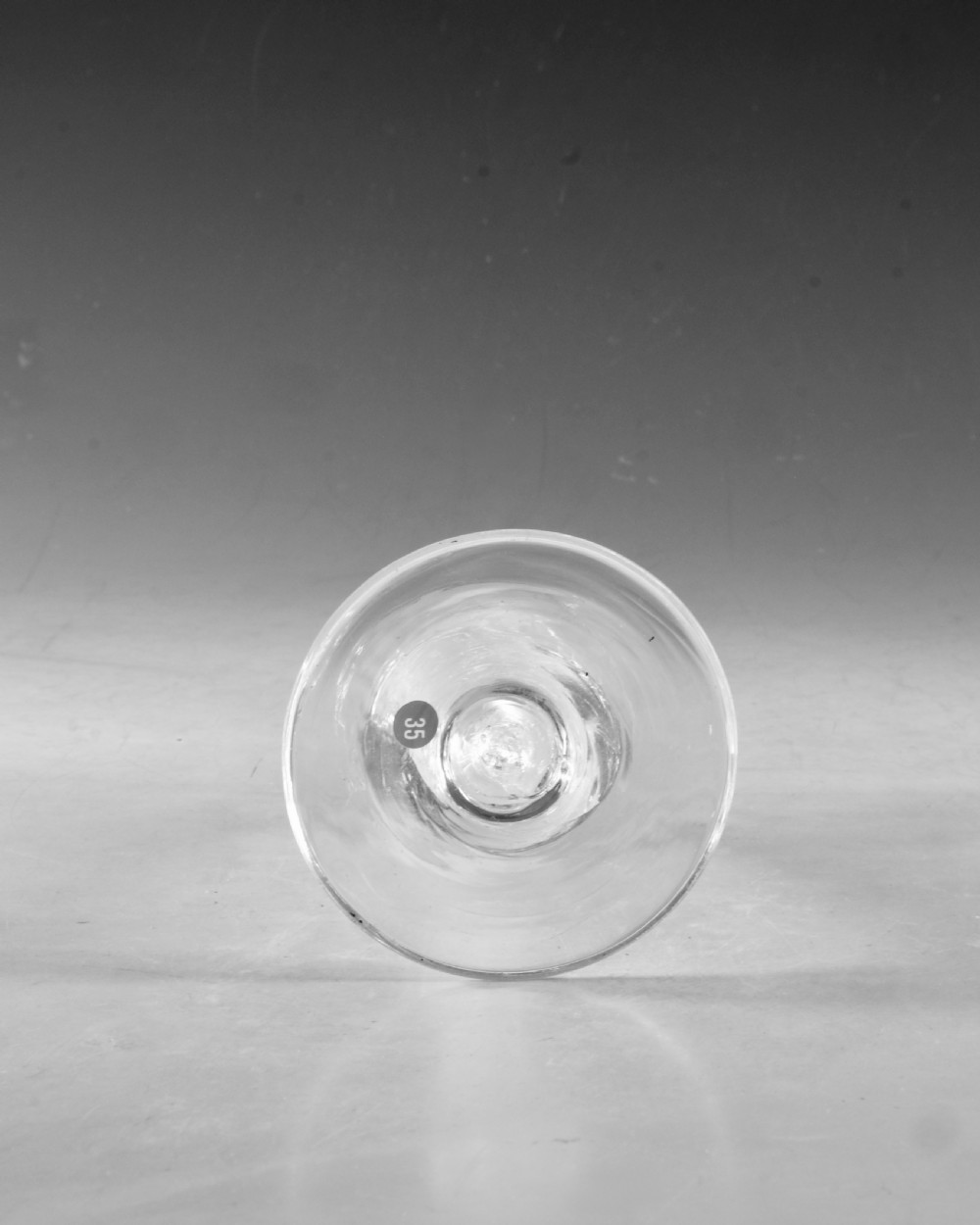 An 18th-century English clear glass cordial featuring a small round funnel bowl, a dense air twist stem, and a flat conical foot. View VI
