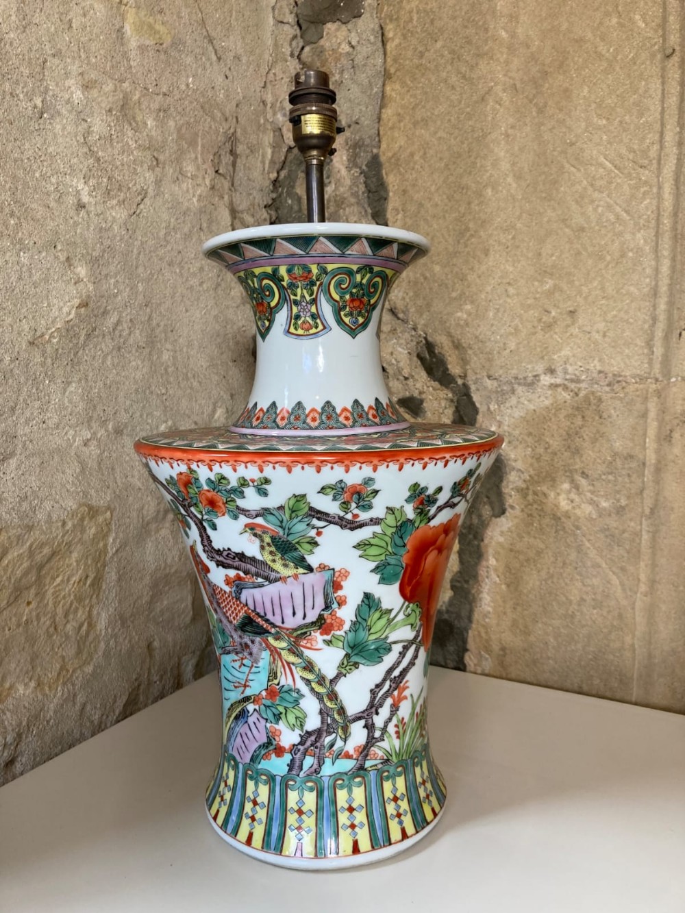 A large hand-painted Chinese porcelain table lamp decorated with colourful bird and flora enamels, topped with a brass bulb socket.