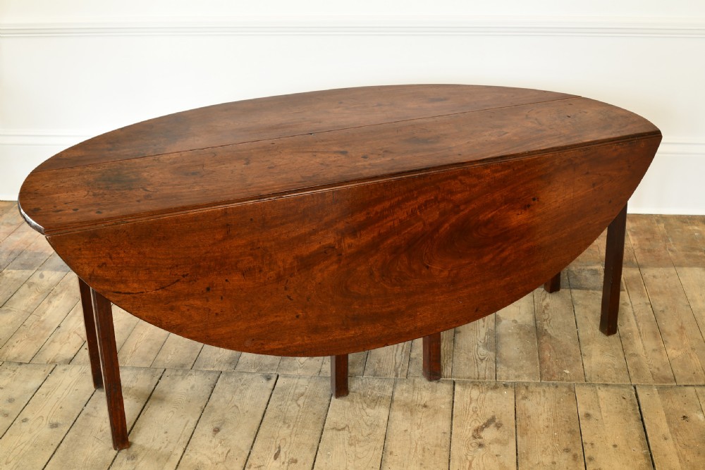 An 18th-century Irish mahogany hunt table featuring an oval drop-leaf top supported by straight wooden legs. View V