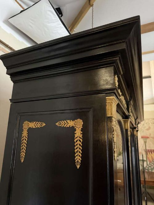 A large late 19th-century French Empire style ebonised bookcase with three arched glass doors, gilt bronze mounts, and light oak shelves. View VI