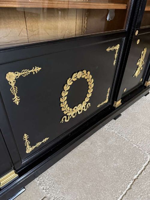 A large late 19th-century French Empire style ebonised bookcase with three arched glass doors, gilt bronze mounts, and light oak shelves. View X