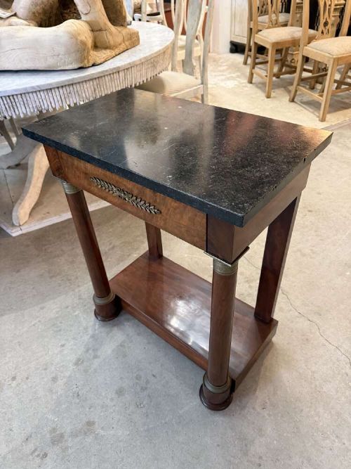 A small late nineteenth-century French Empire style mahogany console table featuring a black marble top, cylindrical column legs with metallic accents, a single frieze drawer with a brass laurel mount, and a lower shelf. View II