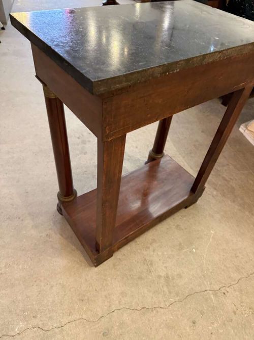 A small late nineteenth-century French Empire style mahogany console table featuring a black marble top, cylindrical column legs with metallic accents, a single frieze drawer with a brass laurel mount, and a lower shelf. View IV